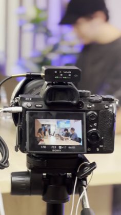 Écran d'un appareil photo sur trépied filmant une scène de travail dans un logement