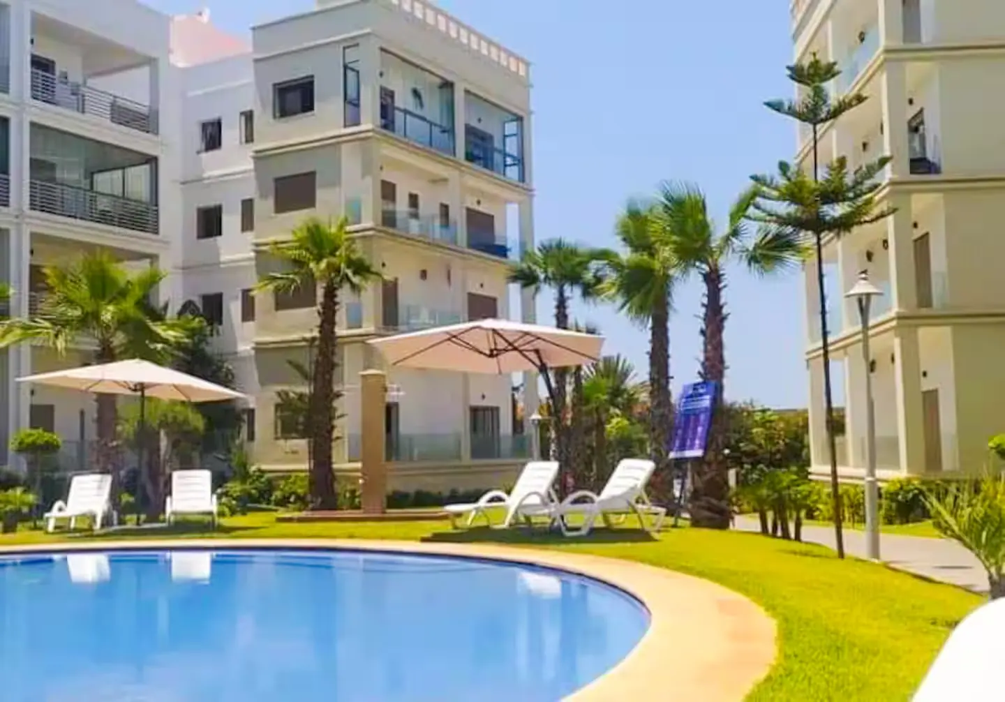 Résidence balnéaire avec piscine, transats et palmiers sur la côte près de Rabat, logement en gestion dans le réseau