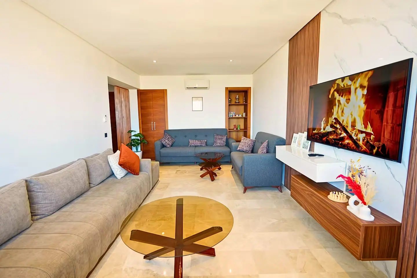 Grand salon lumineux d'un appartement à Casablanca avec canapés, écran mural et sol en marbre clair