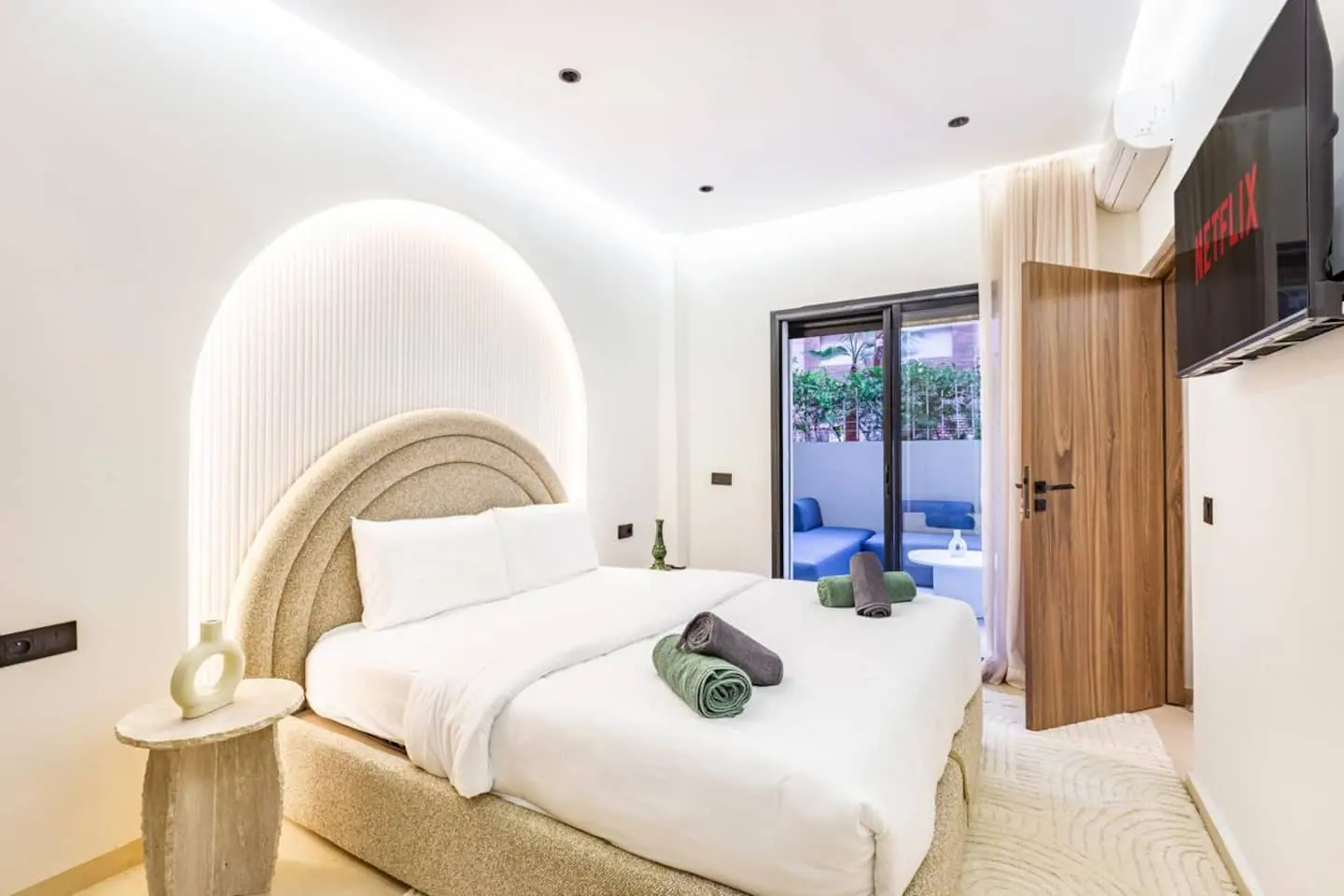 Chambre design d'un appartement à Marrakech avec tête de lit arrondie et serviettes roulées posées sur le lit