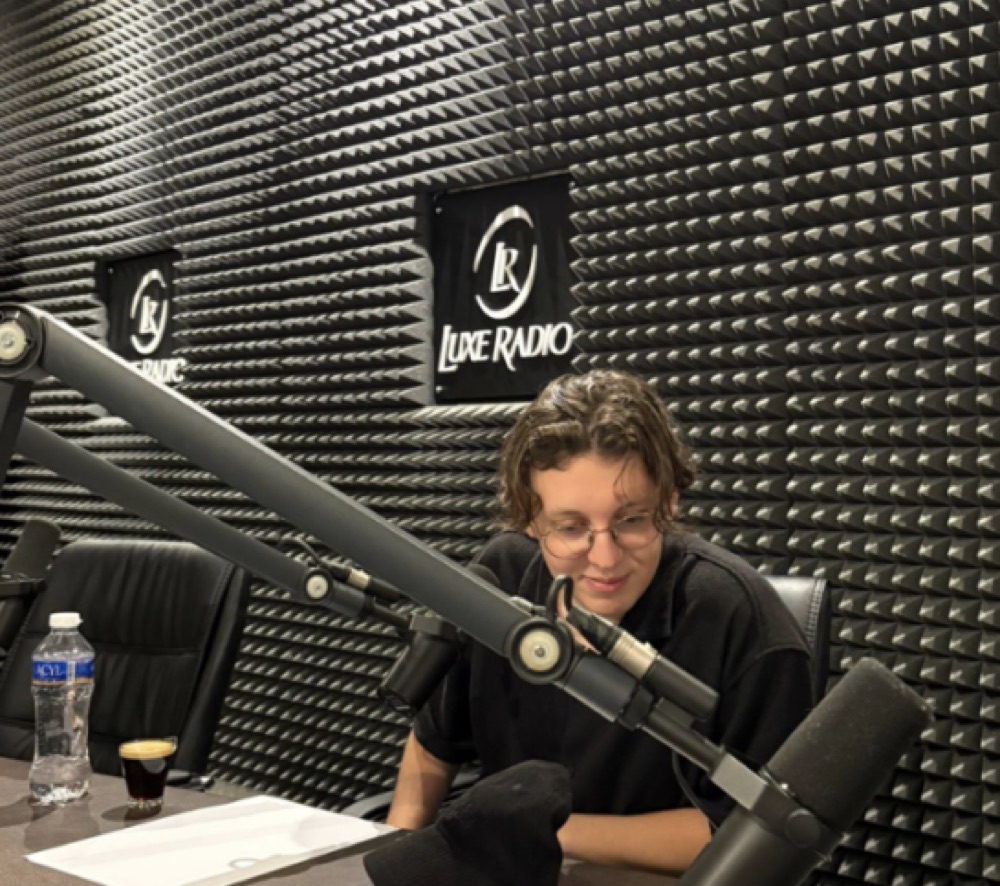 Reda Bennani Khir au micro dans le studio de Luxe Radio à Casablanca, devant les fanions de la station